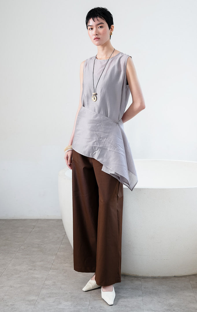 Atasan wanita tanpa lengan bahan kain halus ringan warna abu-abu (grey sleeveless top) Jaide Top dengan kerah bulat sederhana dan detail lapisan luar lilitan yang dapat dilepas pasang di bagian pinggang (detachable wrap layer at the waist).