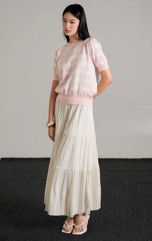 Jourdan Top Pink, atasan rajut lengan pendek motif garis pink dan putih dengan detail tekstur rajutan unik, dipadukan dengan rok panjang putih