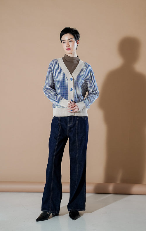 Katniss cardigan Rajut V-neck warna biru tua (dark blue) dengan motif garis diagonal, dipadukan dengan inner kerah tinggi dan celana jeans.