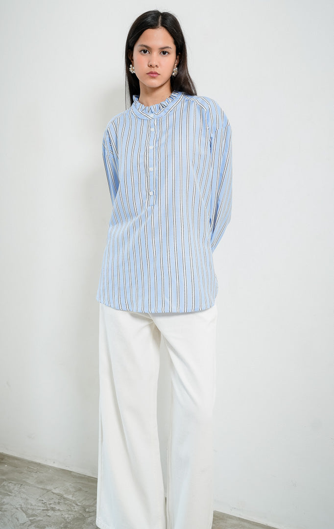 Blus wanita lengan panjang motif garis-garis biru (blue striped) Kellie Top berbahan kain tenun ringan (lightweight woven fabric) dengan kerah berdiri aksen kerut (ruffled stand neckline), bukaan setengah kancing depan (half-placket), dan kelim melengkung (curved hem).