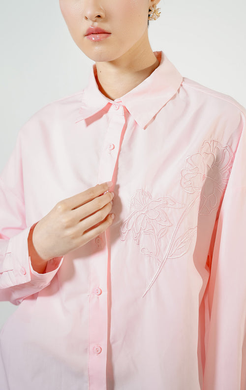Detail dekat model mengenakan Zinnia Floral Embroidery Detail Shirt warna pink, atasan kemeja katun wanita lengan panjang warna merah muda pastel dengan bordir motif bunga minimalis di dada.