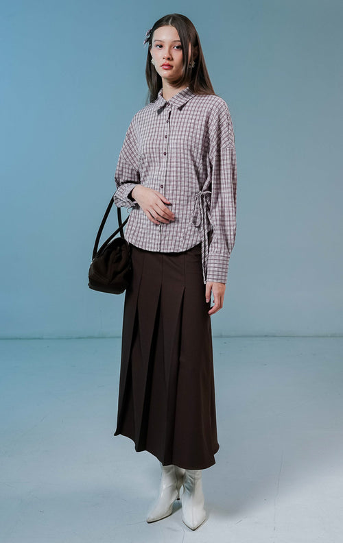 Model wanita mengenakan Fawn Plaid Top warna ungu (purple), kemeja katun lengan panjang motif kotak-kotak klasik dengan detail tali serut di bagian samping.