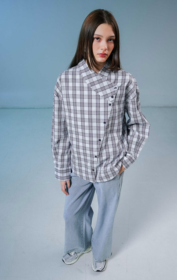 Model wanita mengenakan Joseph Plaid Top warna blue, kemeja katun lengan panjang motif kotak-kotak dengan detail kerah tinggi dan kancing asimetris depan.