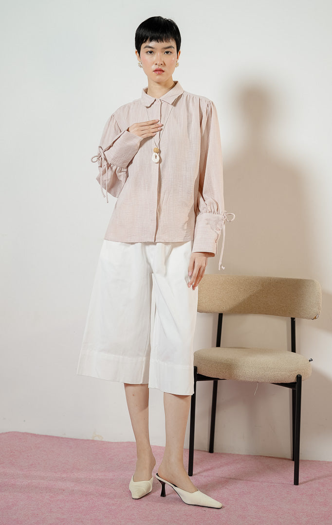 Detail dekat lengan Madden Ribbon-Detail Long-Sleeve Shirt warna pink, kemeja blouse wanita warna merah muda pastel dengan manset panjang berdetail tali pita simpul yang feminin.