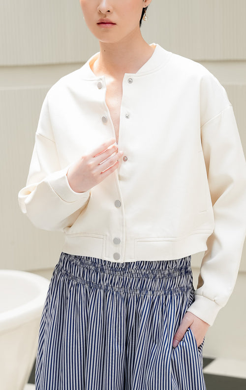 Jaket bomber wanita Larra Jacket warna ivory dengan kerah stand-up ribbed, kancing depan, dan siluet terstruktur style modern & casual.