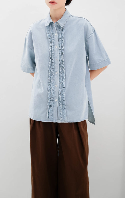Kemeja denim wanita warna biru muda (light denim) Lavender Top dengan detail kerah klasik, aksen ruffle trim di sepanjang kancing depan, dan siluet relaxed fit.