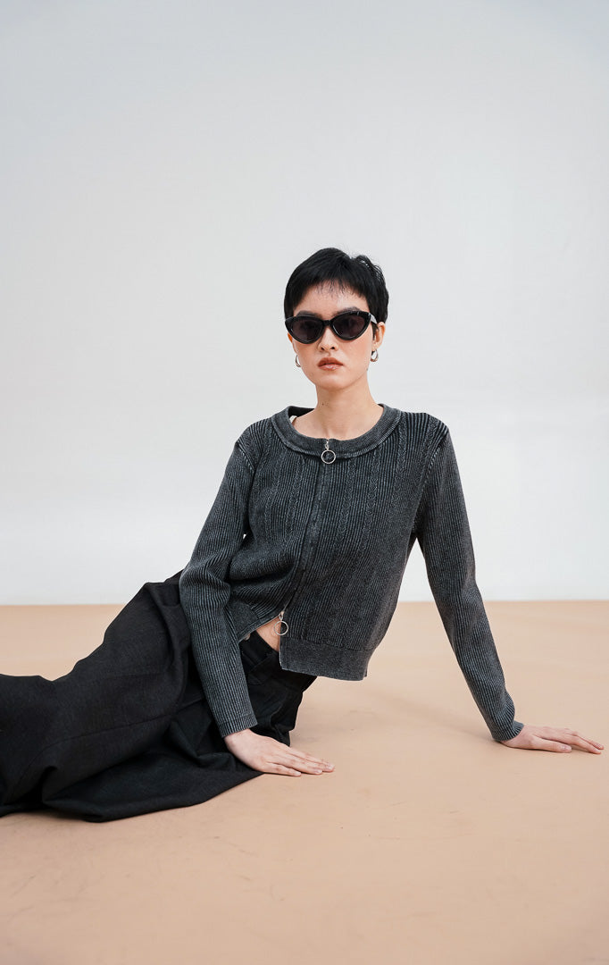 Model mengenakan Leona Cardigan warna grey, kardigan rajut bertekstur kabel dengan dua resleting (double zip) perak di bagian depan dan kerah bulat.