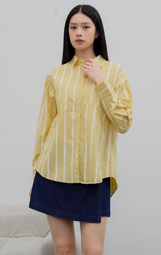 Kemeja wanita oversized lengan panjang warna kuning (yellow) Linette Top bermotif garis vertikal (striped) berbahan campuran katun-poliester dengan saku depan fungsional.