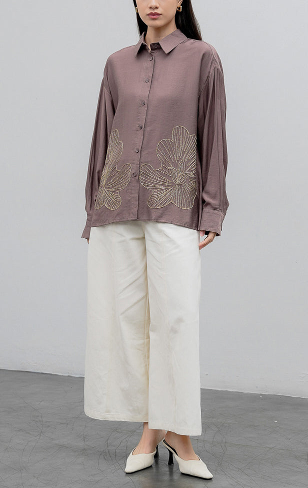 Kemeja lengan panjang wanita warna cokelat keabu-abuan (taupe) Loletta Top berbahan campuran linen-poliester (linen-polyester blend) dengan aksen bordir lurex berkilau (shimmer) di bagian bawah dan bukaan kancing depan.