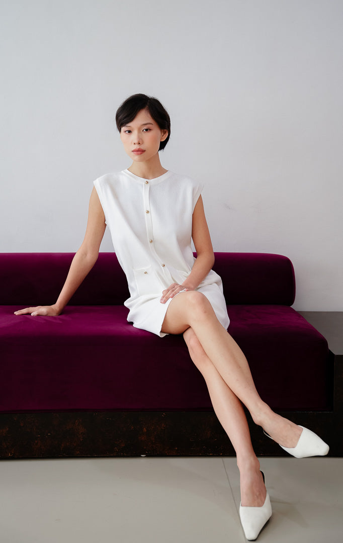 Mini dress wanita tanpa lengan (sleeveless) warna putih Luvenia Dress berbahan stretch knit dengan aksen kancing depan dan kantong fungsional untuk gaya casual dan date night.