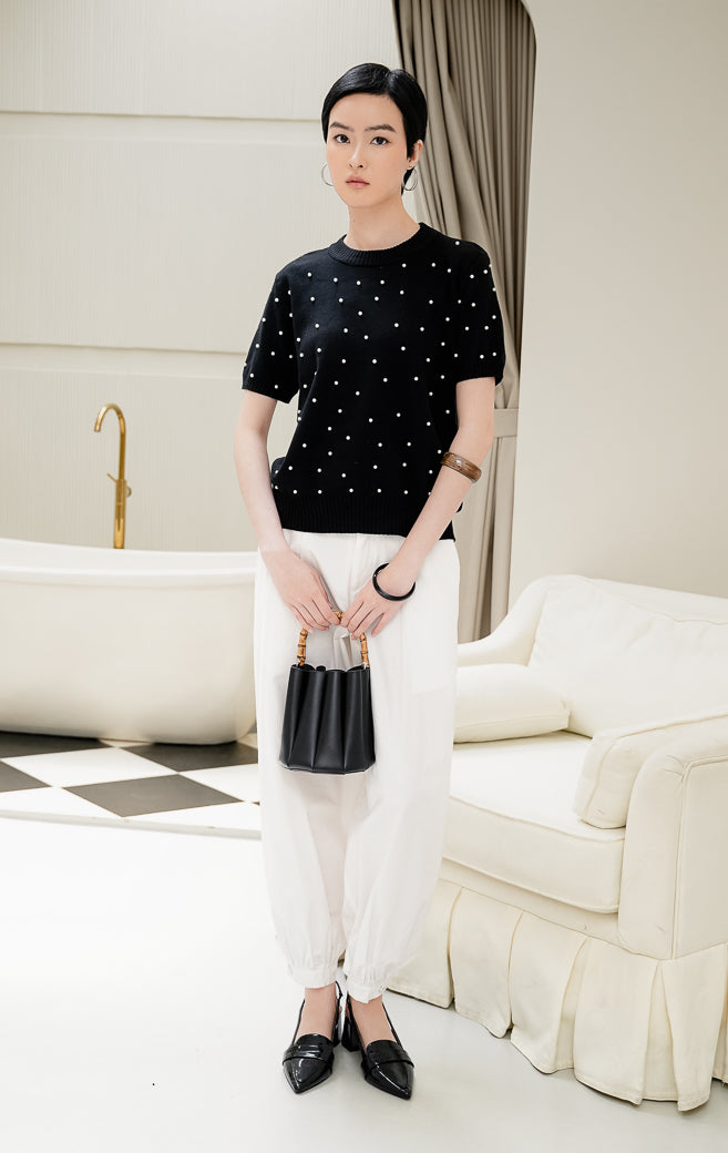 Atasan rajut wanita warna hitam Maple Top dengan aksen hiasan mutiara pearl studded, kerah bulat crew neck, dan lengan pendek yang elegan.