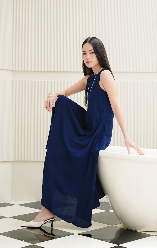 Long dress wanita tanpa lengan (sleeveless) warna navy Marcheta Dress dengan siluet A-line, kerah bulat (round-neck), dan resleting belakang.