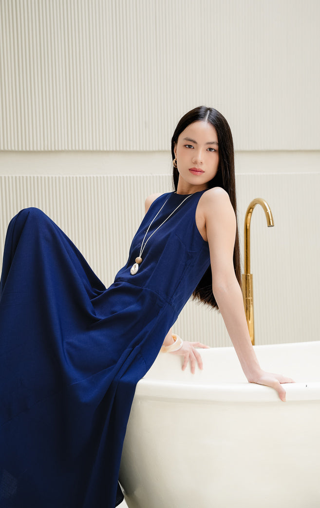 Long dress wanita tanpa lengan (sleeveless) warna navy Marcheta Dress dengan siluet A-line, kerah bulat (round-neck), dan resleting belakang.
