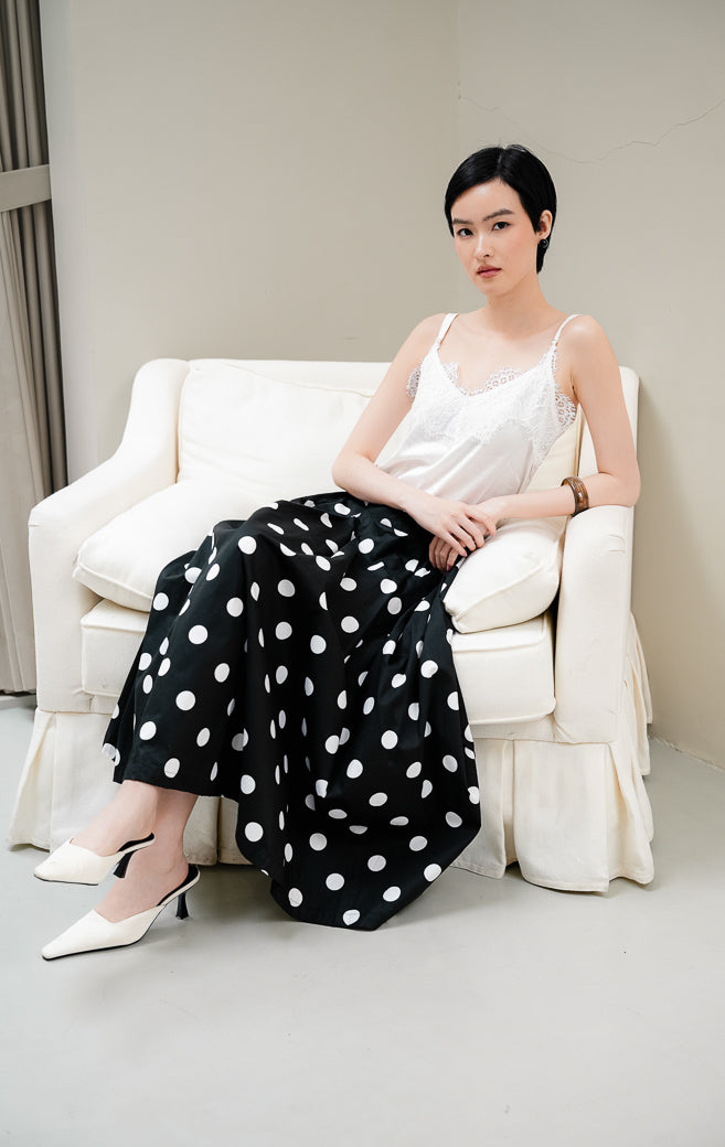 Rok panjang wanita Maroline Skirt warna black (hitam) motif polka dot putih model flare maxi berbahan cotton dengan pinggang karet dan saku fungsional.