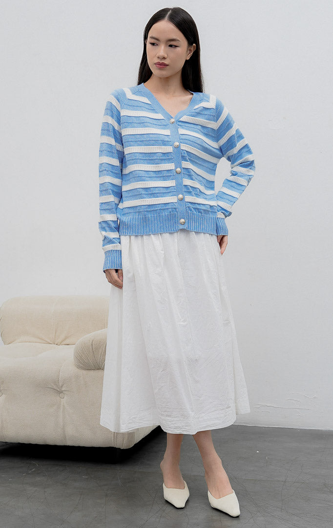 Kardigan rajut wanita lengan panjang warna biru muda (light blue) Matera Cardigan bermotif garis horizontal putih (striped) dengan kerah V (V-neck) dan kancing emas.