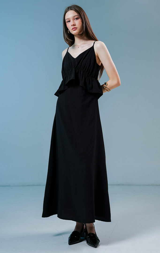 Model wanita mengenakan Haven V-Neck Ruffle Peplum Maxi Dress warna hitam, gaun panjang long dress wanita dengan detail kerut peplum dan tali spageti.