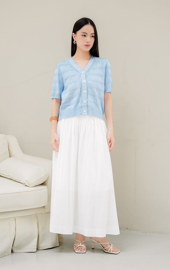 Atasan rajut wanita warna biru muda Maysie Top dengan motif rajut geometris lattice, kerah V-neck, lengan pendek, dan kancing depan elegan.