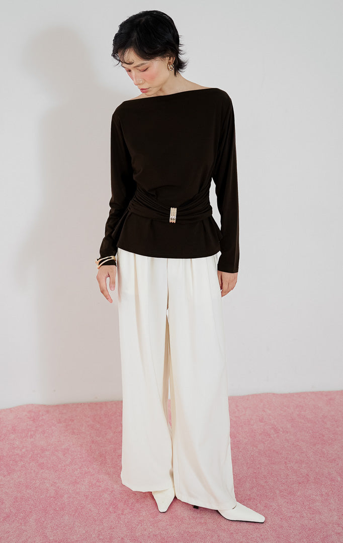 Atasan wanita Mezza Top warna cokelat tua dari This Is April dengan kerah model boat neck, detail kerutan di pinggang (gathered waist), dan aksen bros emas.