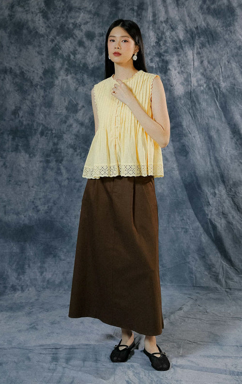 Atasan tanpa lengan wanita Misty warna kuning (yellow) berpotongan peplum, menampilkan detail lipit pintuck dada, aksen sulam (embroidery), dan kancing depan hidup.