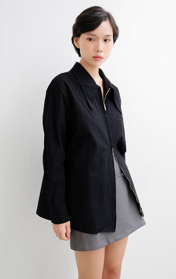 Atasan kemeja wanita warna hitam Myra Top berbahan katun ringan dengan kerah oversized sailor, bukaan resleting depan (front zipper), dan kantong dada