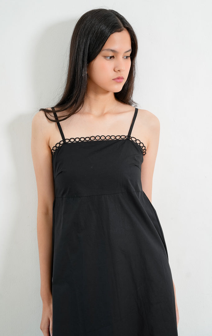 Dress wanita model A-line warna hitam (black A-line dress) Nicolle Dress dengan detail hiasan lingkar benang (loop trim detailing) di bagian garis leher, tali bahu spaghetti yang dapat disesuaikan (adjustable spaghetti straps), serta siluet ringan bertekstur.
