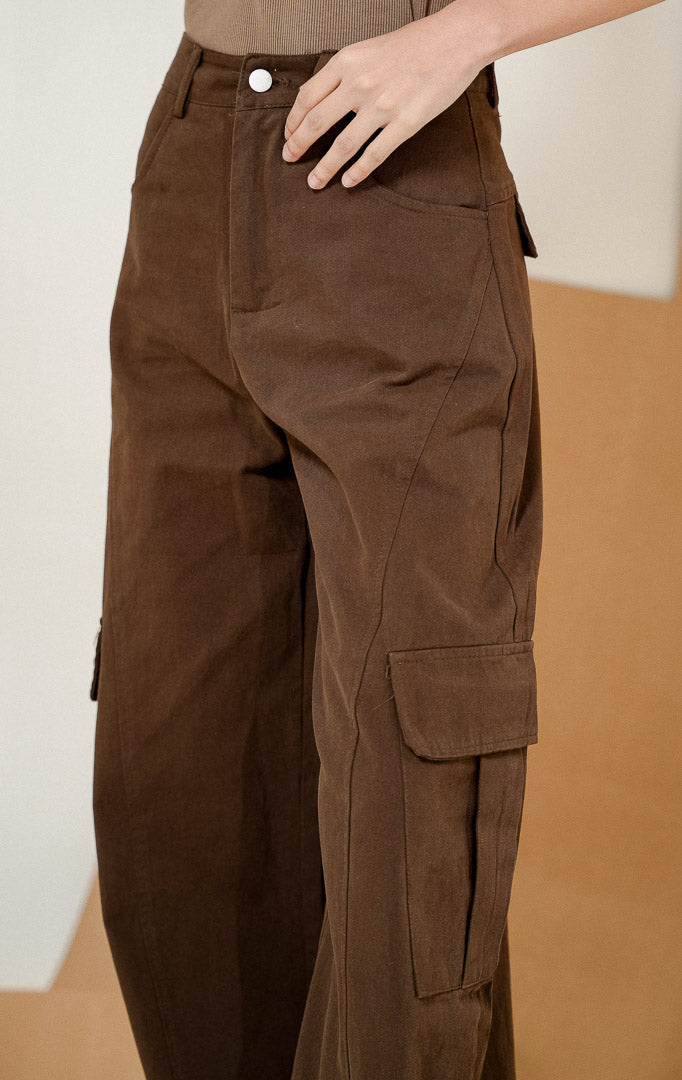 Model berpose menghadap samping belakang mengenakan Oliviana Classic Cargo Pants Dark Brown, produk celana panjang cargo wanita warna cokelat tua dengan detail saku kantong samping.