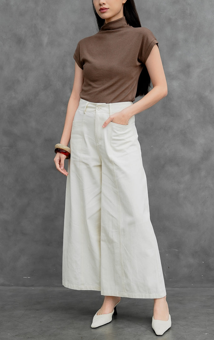 Celana panjang wanita model lebar (wide-leg pants) warna krem muda (ivory) Orian Pants berbahan cotton twill dengan jahitan panel melengkung (curved panel lines), saku utility depan, dan kancing resleting.