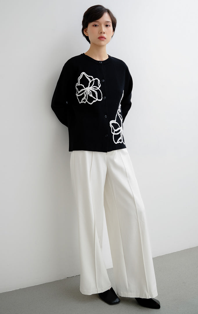 Cardigan rajut wanita warna hitam Peppie Cardigan berbahan soft stretch dengan detail bordir bunga (flower embroidery) dan kancing depan (button-up).