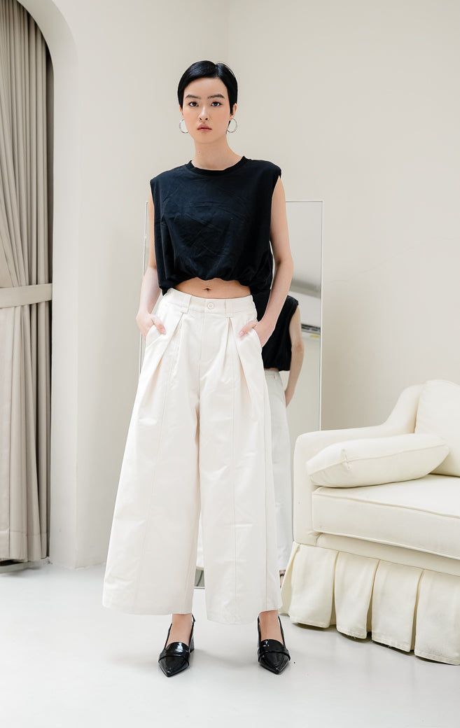 Celana panjang wanita Renata Wide-Leg Pants warna ivory (gading) berpotongan wide-leg dengan detail lipit depan (front pleats), kancing depan, dan pinggang karet belakang untuk tampilan smart-casual.