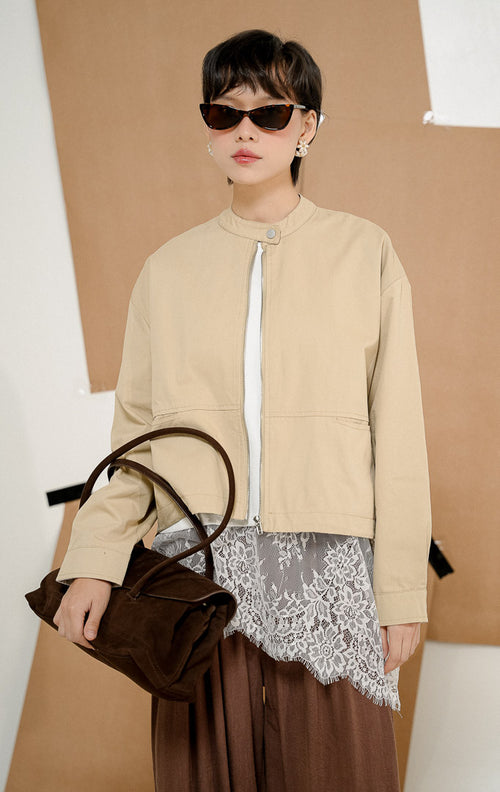 Model mengenakan Renley Crop Bomber Jacket Khaki, produk jaket bomber wanita potongan crop lengan panjang warna khaki krem dengan kerah shanghai dan resleting depan.