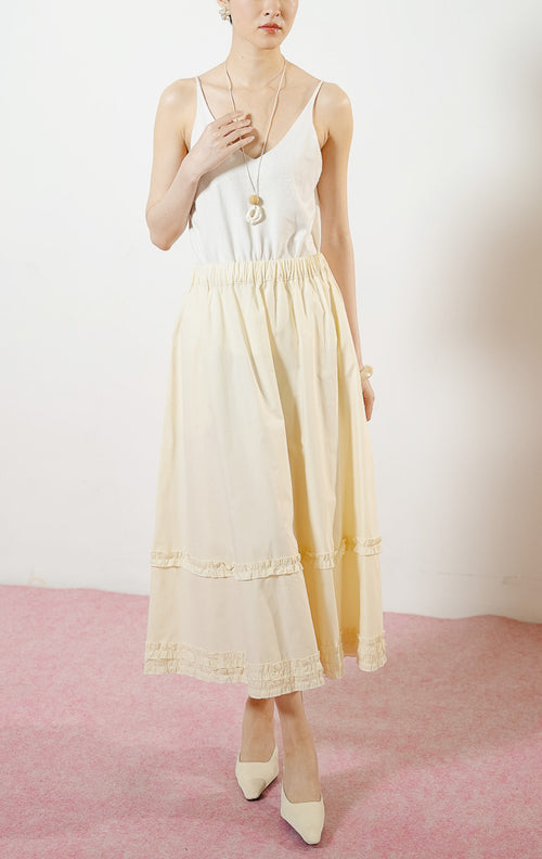 Model wanita mengenakan Arabella Skirt warna ivory, rok midi panjang wanita berwarna putih tulang dengan pinggang karet dan detail aksen kerut ruffle horizontal.