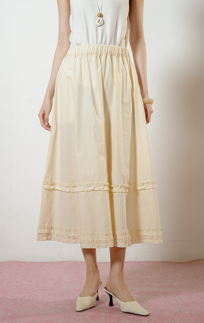Model wanita mengenakan Arabella Skirt warna ivory, rok midi panjang wanita berwarna putih tulang dengan pinggang karet dan detail aksen kerut ruffle horizontal.