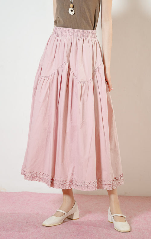 Model wanita mengenakan Lacey Tiered Ruffle Hem Skirt warna dusty pink, rok panjang katun wanita berwarna merah muda dengan pinggang karet dan detail kelim kerut rumbai yang feminin.