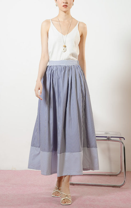 Model wanita mengenakan Skandar Contrast Hem Striped Maxi Skirt warna navy, rok panjang katun wanita motif garis salur biru dongker dengan variasi arah garis horizontal kontras di ujung bawah