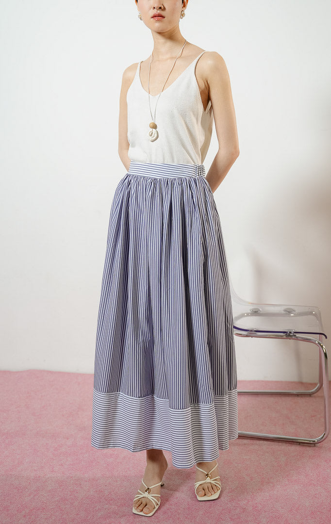 Model wanita mengenakan Skandar Contrast Hem Striped Maxi Skirt warna navy, rok panjang katun wanita motif garis salur biru dongker dengan variasi arah garis horizontal kontras di ujung bawah