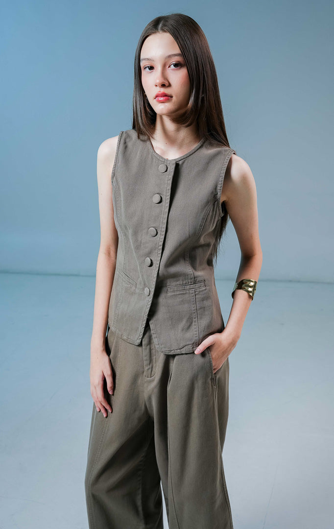 Model wanita mengenakan Rielle Two-Pocket Button-Up Vest warna brown, atasan rompi vest denim wanita berwarna coklat dengan kancing depan dan detail kantong samping.