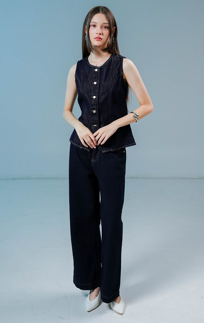 Model wanita mengenakan Vior Button-Up Vest warna dark denim, atasan rompi vest denim wanita berwarna biru dongker gelap dengan detail kancing depan logam.