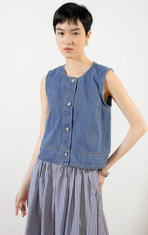 Model wanita mengenakan Klyne Round-Neck Button Vest Denim, atasan rompi vest denim wanita berwarna biru dengan potongan kerah bulat dan kancing depan logam.