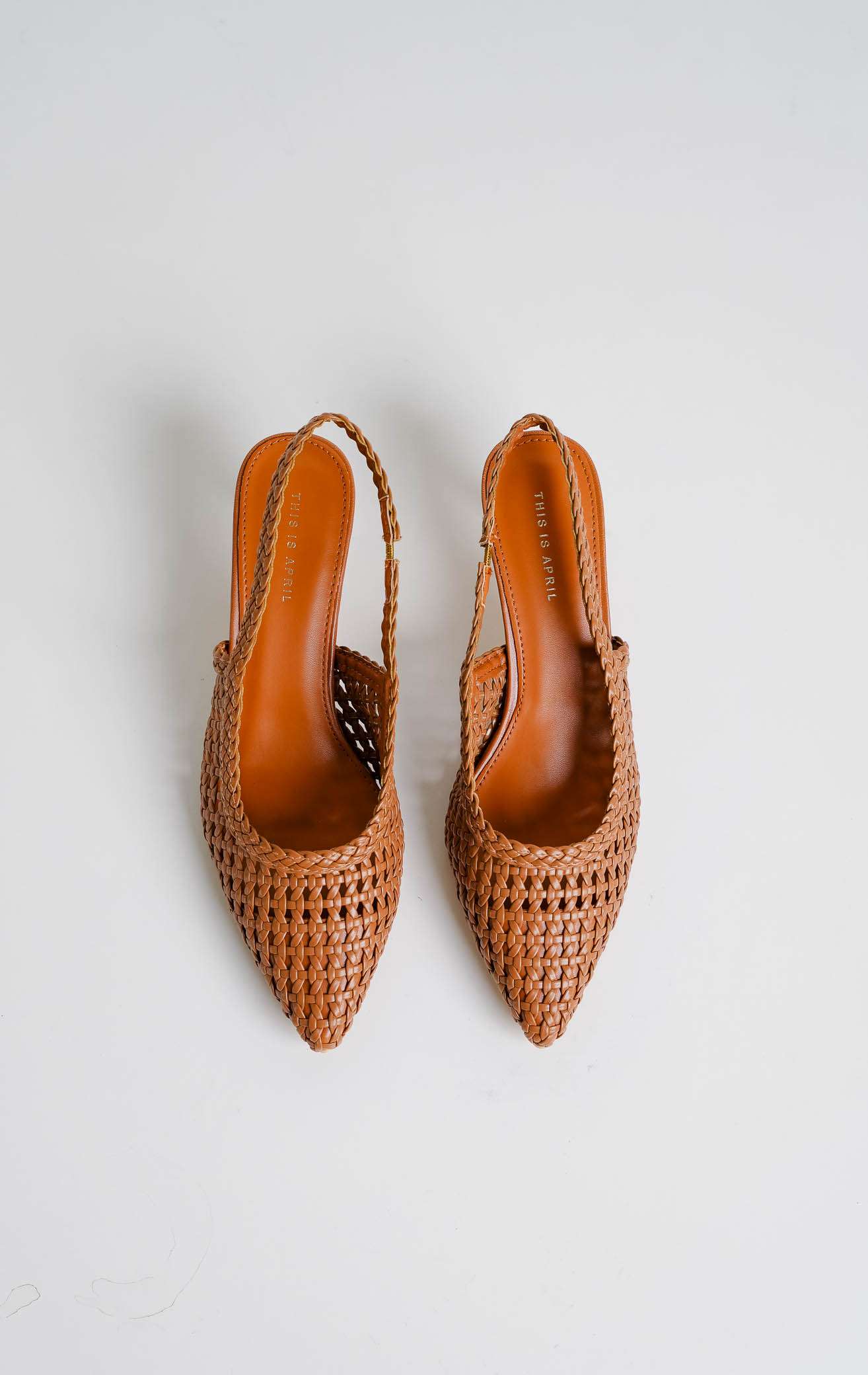 Tampilan flat lay sepasang Avaia Heels warna camel, sepatu hak rendah wanita model slingback heels ujung runcing pointed toe bahan kulit anyaman warna cokelat tan dari This Is April.