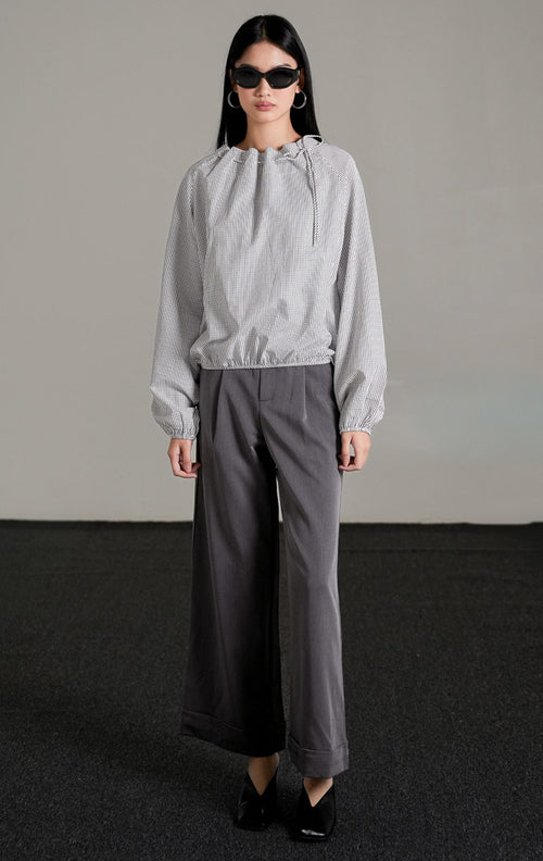 Seraph Top White, atasan katun putih motif kotak grid halus dengan leher serut (drawstring), dipadukan dengan celana kulot abu-abu dan kacamata hitam.