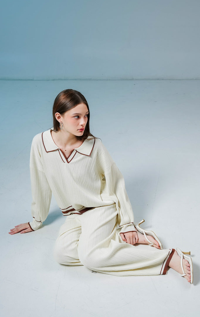 Model wanita mengenakan Margarite Contrast Trim Ribbed Collared Knit Set warna ivory, setelan one set rajut wanita lengan panjang bertekstur rib dengan detail garis kontras cokelat.