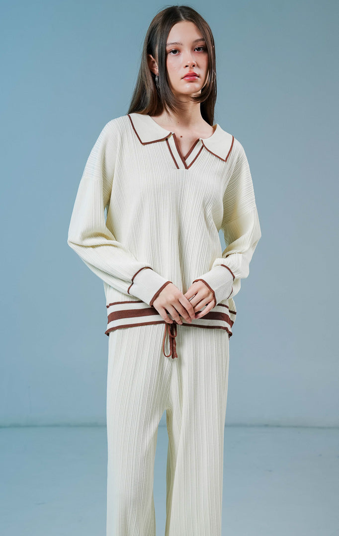 Model wanita mengenakan Margarite Contrast Trim Ribbed Collared Knit Set warna ivory, setelan one set rajut wanita lengan panjang bertekstur rib dengan detail garis kontras cokelat.