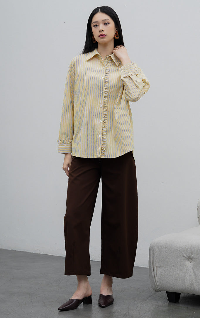 Kemeja katun wanita lengan panjang warna kuning (yellow) Sevran Top berkerah dengan motif garis vertikal (vertical stripes), detail rumbai (ruffle trim), dan bukaan kancing depan.