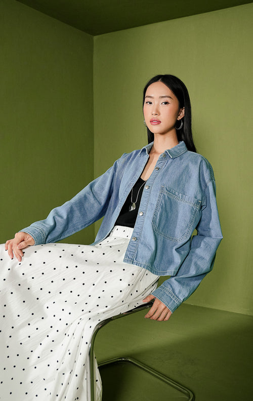 Atasan kemeja wanita Silfira Top berbahan denim warna biru klasik lengan panjang, dilengkapi kerah rapi, deretan kancing metal di bagian depan, serta satu saku fungsional di dada sebelah kiri.