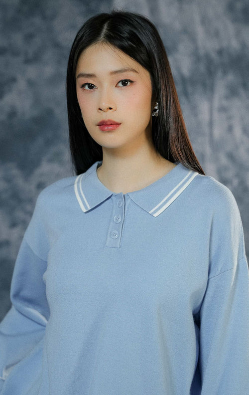 Atasan baju rajut wanita Sinclair warna biru muda (light blue) lengan panjang berkerah polo dengan paduan list garis putih dan keliman ruffle yang manis.