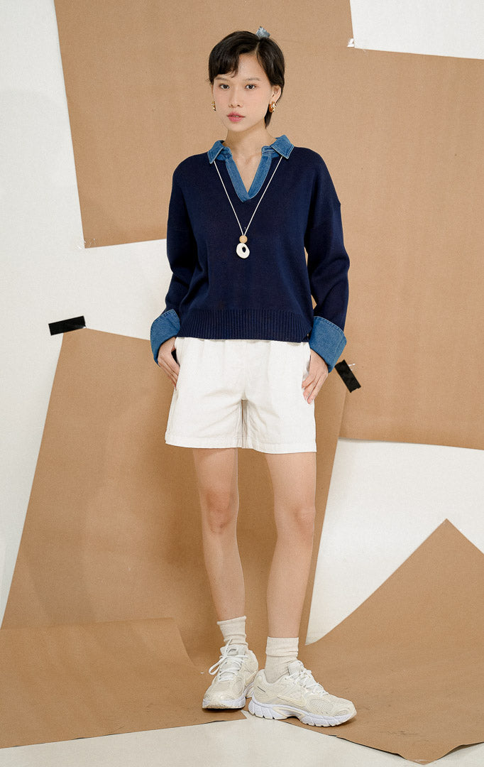 Model berdiri mengenakan Sophia Denim Collar Knit Sweater Navy, produk sweater rajut wanita lengan panjang warna biru dongker dengan variasi kerah kemeja dan manset lengan denim.