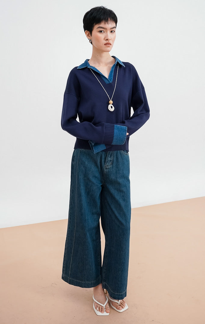 Close-up model mengenakan Sophia Sweater warna navy, menampilkan detail kerah denim biru yang kontras dengan bahan rajut halus dan kalung statement.