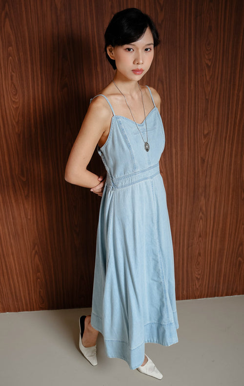 Maxi dress wanita berbahan denim warna biru muda (light denim) Sorelle Dress dengan siluet flowy dan tali bahu yang bisa disesuaikan (adjustable straps).