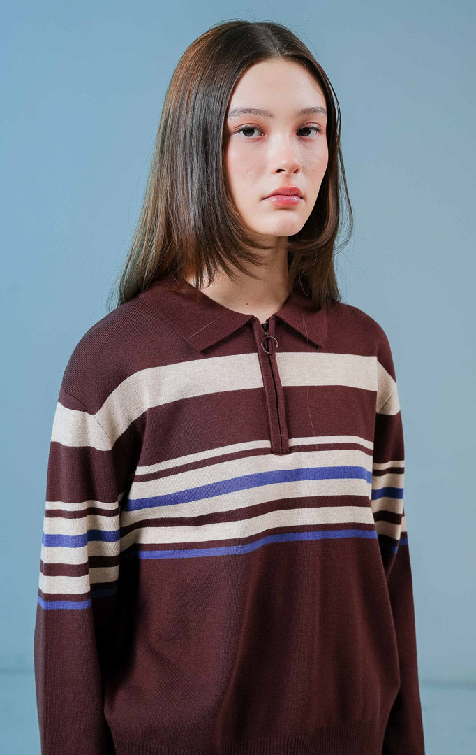 Model wanita mengenakan Bennet Striped Collared Sweater warna coklat, sweater rajut lengan panjang yang nyaman dengan motif garis horizontal dan kerah half-zip.