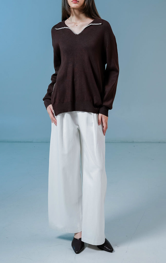 Model wanita mengenakan Maddox V-Neck Contrast Stitch Collared Sweater warna brown, baju sweater rajut wanita lengan panjang warna coklat tua dengan detail jahitan kontras putih di kerah.